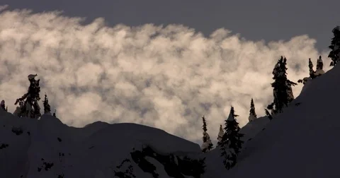 White clouds floating over the snow covered mountains during sunset Stock Footage 77766943