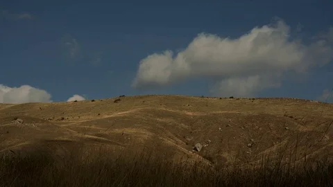 White clouds fly across the blue sky over the rocky hills Stock Footage 72770301