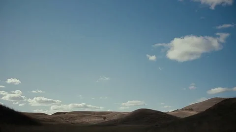 White clouds fly in the blue sky over the hills Stock Footage 76690034