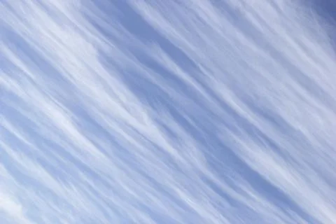 White clouds in form of diagonal stripes on background sky. Stock Photos