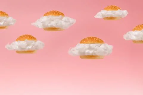 White clouds inside burger buns floating against pink sky background. Stock Photos