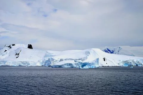 White clouds make the iceberg look whiter. Stock Photos