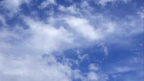 White clouds move gently in a peaceful time lapse over open blue space Stock Footage 321466708