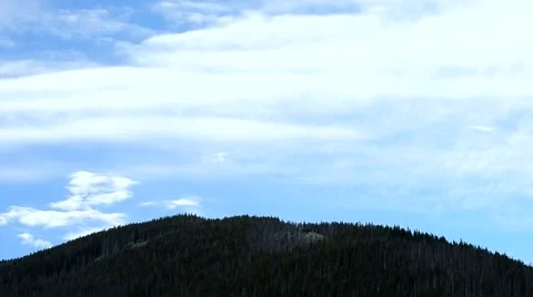 White clouds move over a hill with fir tree forest in mountains Stock Footage 55444975