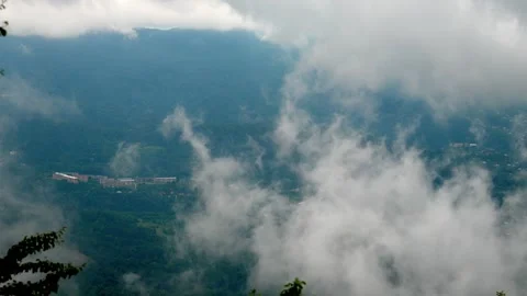 White clouds moving above a green mountain valley with a small town Stock Footage 343995154