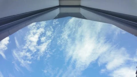 White clouds moving across a blue sky seen through a window Stock Footage 329343196