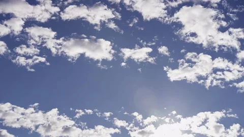 White clouds moving across blue sky with sun flare Stock Footage 329752604