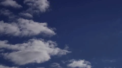 White clouds moving across a deep blue sky timelapse Stock Footage 329751281