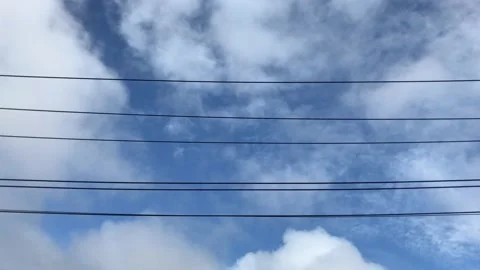 White clouds moving gently in the sky above power lines during the day in Stock Footage 135271112