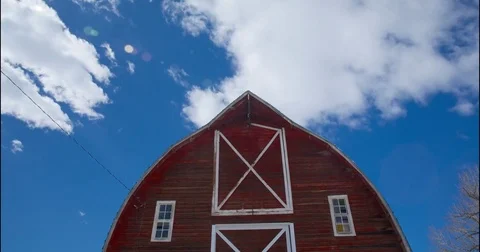 White clouds moving over barn on a sunny day Stock Footage 83885789