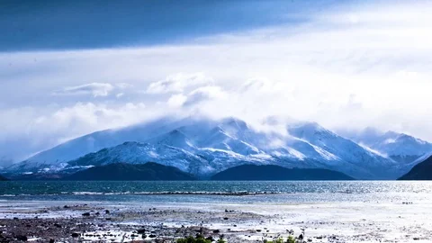 White clouds moving over snow covered mountains and Wanaka lake Stock Footage