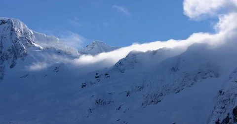 White clouds moving over the snow-covered mountain ranges Stock Footage 77766609