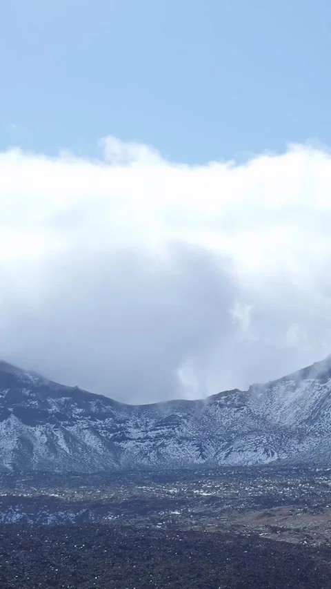 White clouds moving over a snowy volcanic mountain landscape Stock Footage 329864988