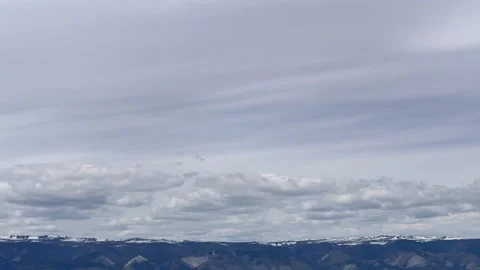 White clouds moving in timelapse over snow capped mountains. Video stock 328336647