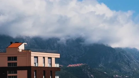 White clouds passing over high mountains with a village located far away Stock Footage 153905978