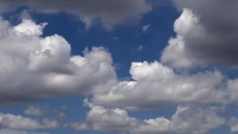 White clouds race through the bright blue sky in a beautiful time-lapse scene Stock Footage 318472299