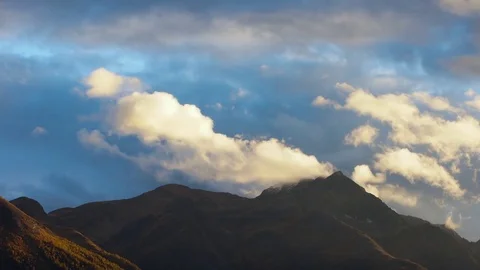 White clouds rolling over the rocky mountains at sunset Stock Footage 76004795