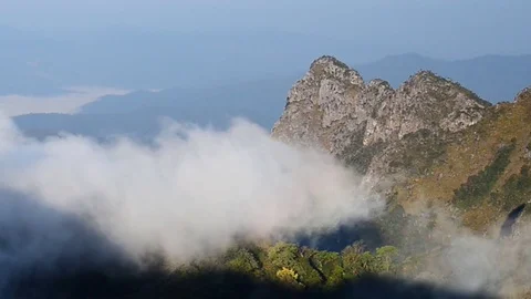 White clouds slowly moves over top mountain. Stock Footage 76636365