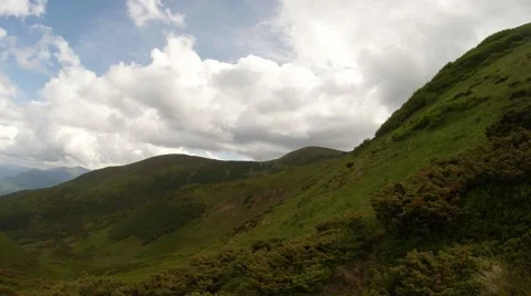 White clouds swim out from behind the green mountains Stock Footage 40618997