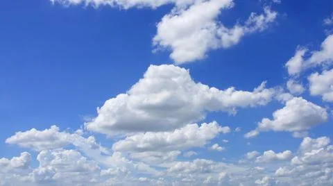 White clouds of various sizes in the bright blue sky. Stock Photos