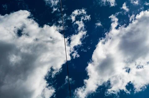 White cloudy clouds against dark blue sky, the sun came out from behind cloud Stock Photos
