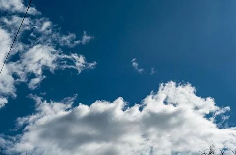 White cloudy clouds against dark blue sky, the sun came out from behind cloud Stock Photos