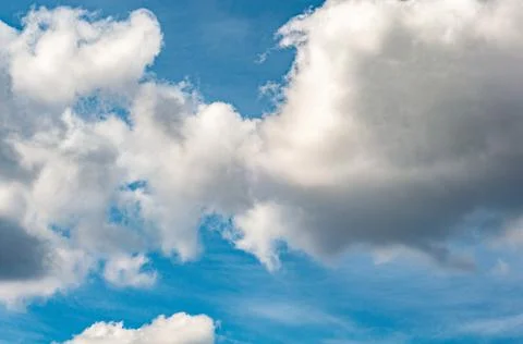White cloudy clouds against dark blue sky, the sun came out from behind clouds. Stock Photos