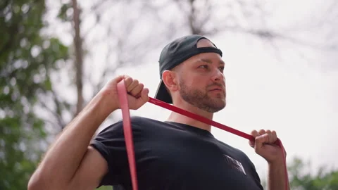 White Coach Demonstrates Shoulder Activation Using Red Resistance Loop, Focused Stock Footage 324756512