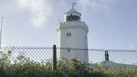 White coastal lighthouse behind metal fence panning Stock Footage 336517352