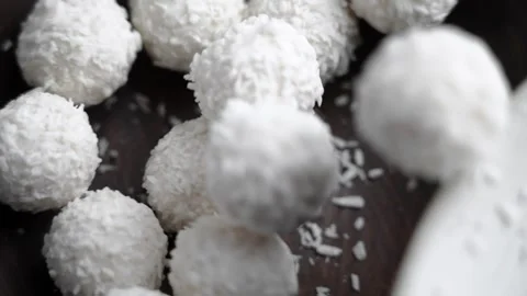 White coconut cream truffles falling into a wooden bowl 動画素材 323298393