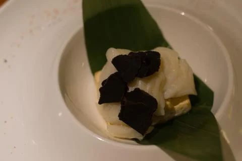 White cod fish with miso sauce and black truffle on a leaf in a a white porce Stock Photos