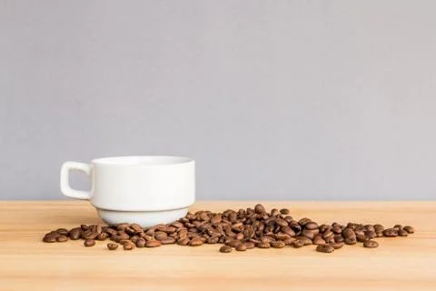 White coffee cup and coffee beans on wooden desk with gray background Stock Photos