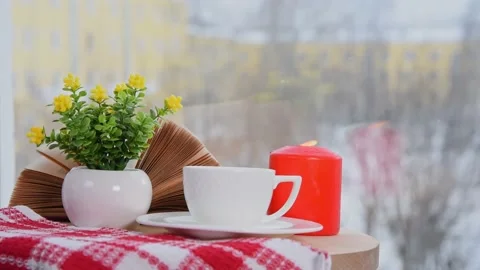 White coffee cup, book, burning candle and vase with flowers on table in cafe. Stock Footage 157626020