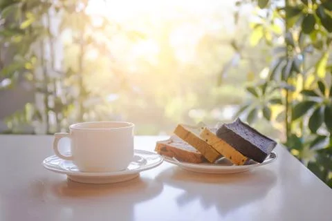 White coffee cup with bread plate on the table with sunlight in the backgroun 스톡 사진