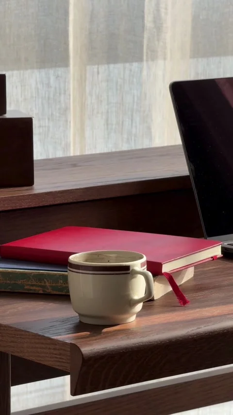 White coffee cup sits by notebook on sunlit desk Video stock 331769890