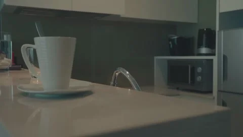 A white coffee cup sits on a white plate on a counter Stock Footage 313371358