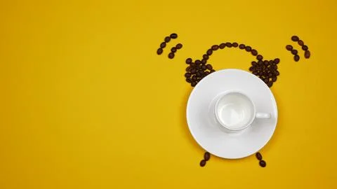 White coffee cup surrounded by coffee beans in the shape of an alarm clock Stock Photos