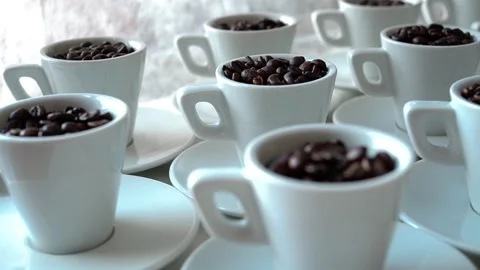 White coffee cups filled with coffee beans arranged on a white table Stock Footage 281791766