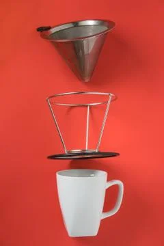 White coffee mug on red background. Metal pour over drip cone pulled apart. Stock Photos
