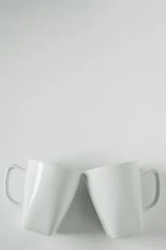White coffee mugs on white background clinking in cheers with empty copy spac Stock Photos