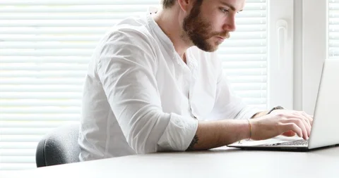 White collar bearded man typing then watching outside Video stock 89645725