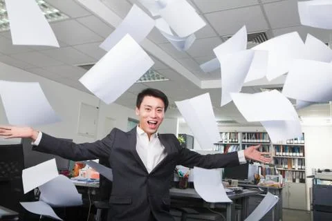 White-collar worker throwing white sheets in air in office Stock-Fotos