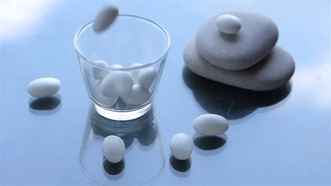 White colored dragee candies fall into a glass in slow motion Video stock 96769365