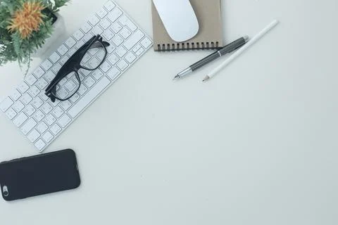 White compact keyboard mouse glasses pen pencil notepad phone flower in a pot on Stock Photos
