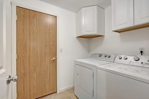 White compact laundry room with cabinets, washing machine and dryer. Northwes Stock Photos
