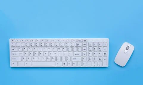 White computer keyboard and mouse on blue background. Stock Photos