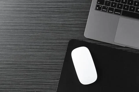 White computer mouse with mousepad and laptop on black wooden table, flat lay Stock Photos