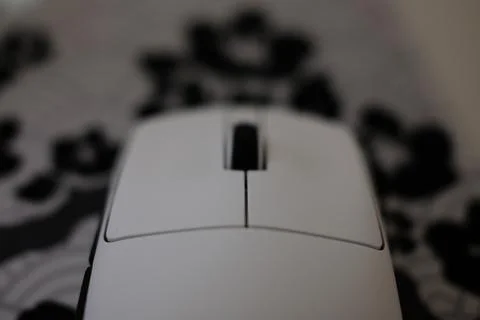 A white computer mouse is on a mousepad. The background is blurry Stock Photos