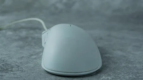 A white computer mouse is placed on a gray table with a concrete texture Stock Photos