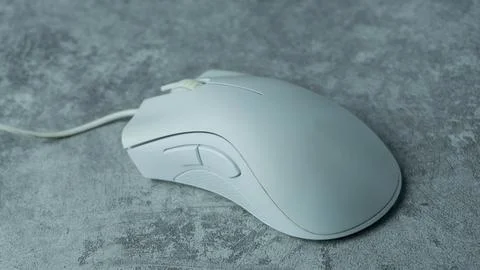 A white computer mouse is placed on a gray table with a concrete texture Stock Photos